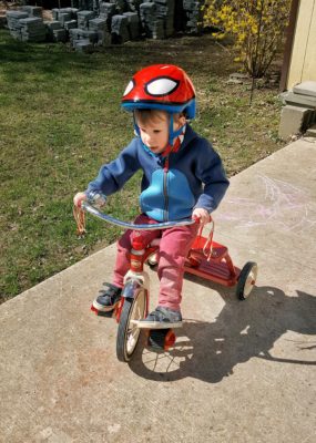 Toddler riding tricycle in the summer