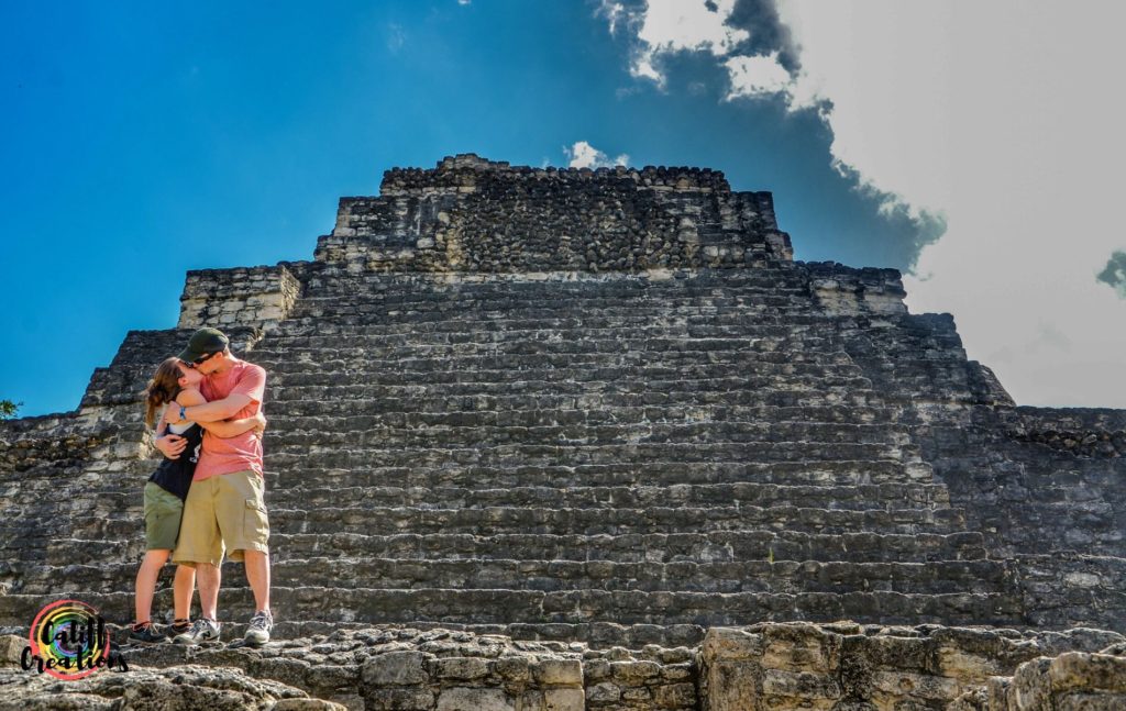 My husband and I kissing in from of a Mayan pyramid at Chacchoben